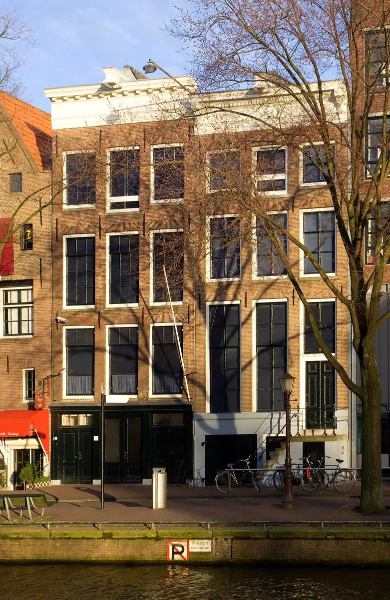 The brick front of the Anne Frank House on the Prinsengracht, with bare trees and bicycles