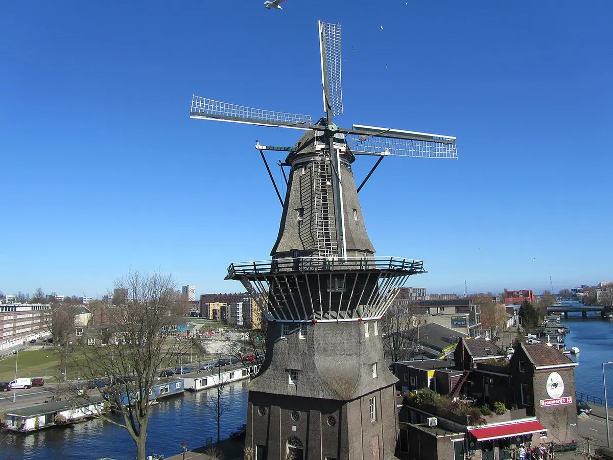 The De Gooyer windmill above the brick building of Brouwerij ’t IJ, by a canal