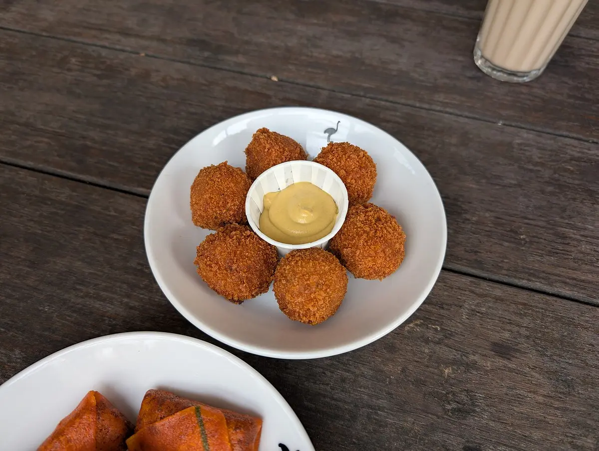 A plate of bitterballen around a small pot of mustard on a café table
