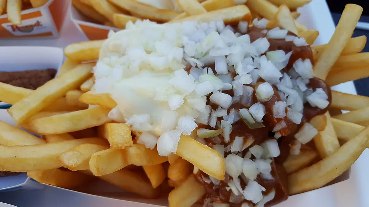 Fries topped with mayonnaise, peanut satay sauce and chopped raw onion