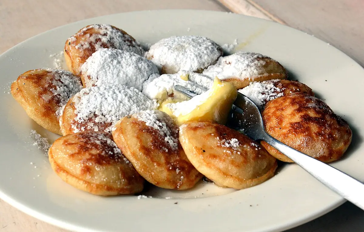 A plate of poffertjes with butter and powdered sugar