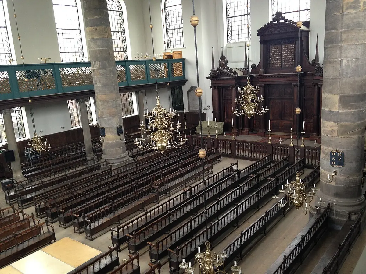 The interior of the Portuguese Synagogue, with wooden benches, brass chandeliers and the ark