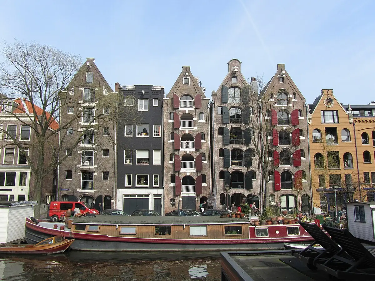 Old gabled warehouses with red shutters along the Brouwersgracht in Amsterdam, houseboats moored in front