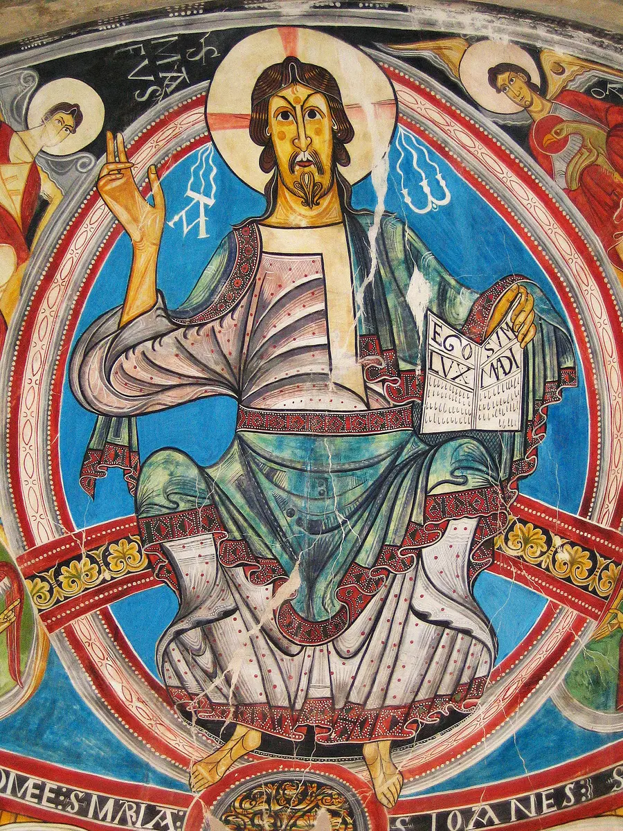 A Romanesque painting of Christ enthroned in an oval of light, holding an open book, in bold reds and blues