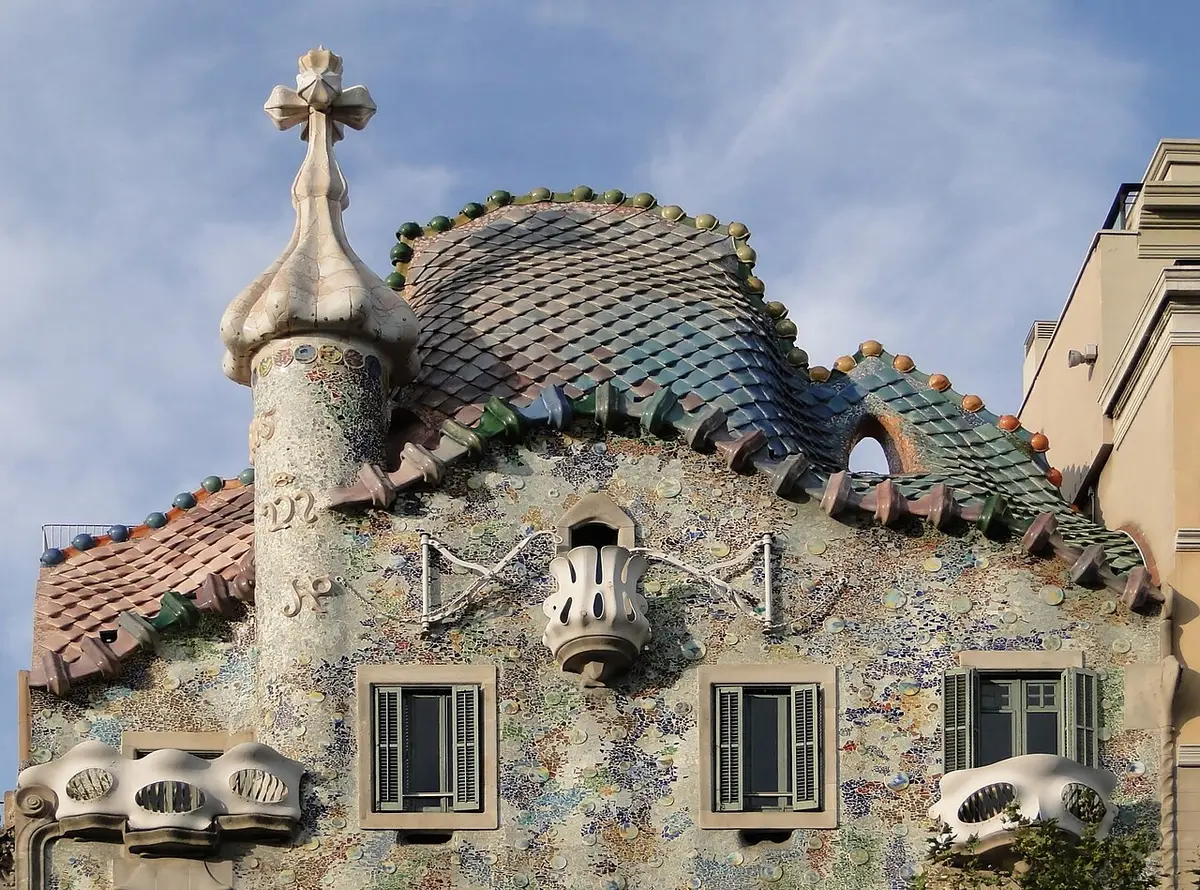 The top of Casa Batlló: a roof of scaled tiles like a dragon’s back, a tower with a cross and walls of broken tile