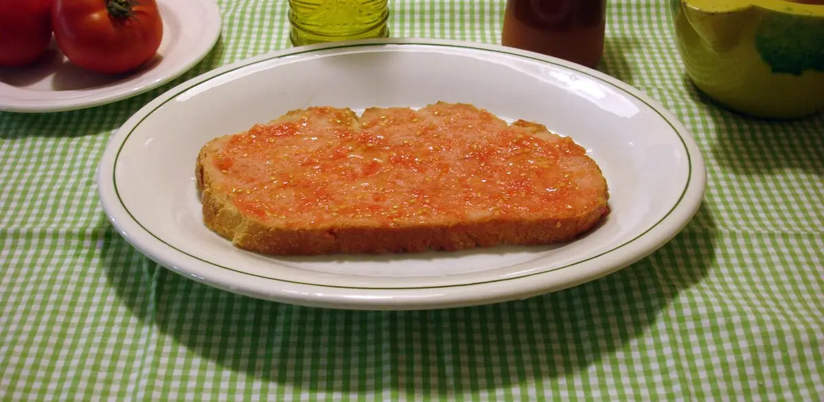 A slice of bread rubbed with tomato and olive oil on a white plate
