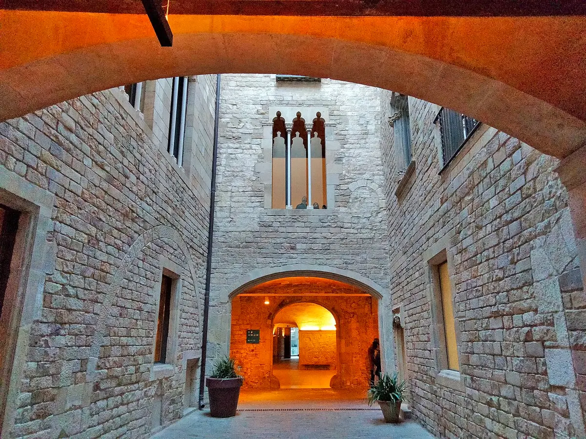 A Gothic stone courtyard seen through an arch in warm light, in one of the palaces of the Picasso Museum