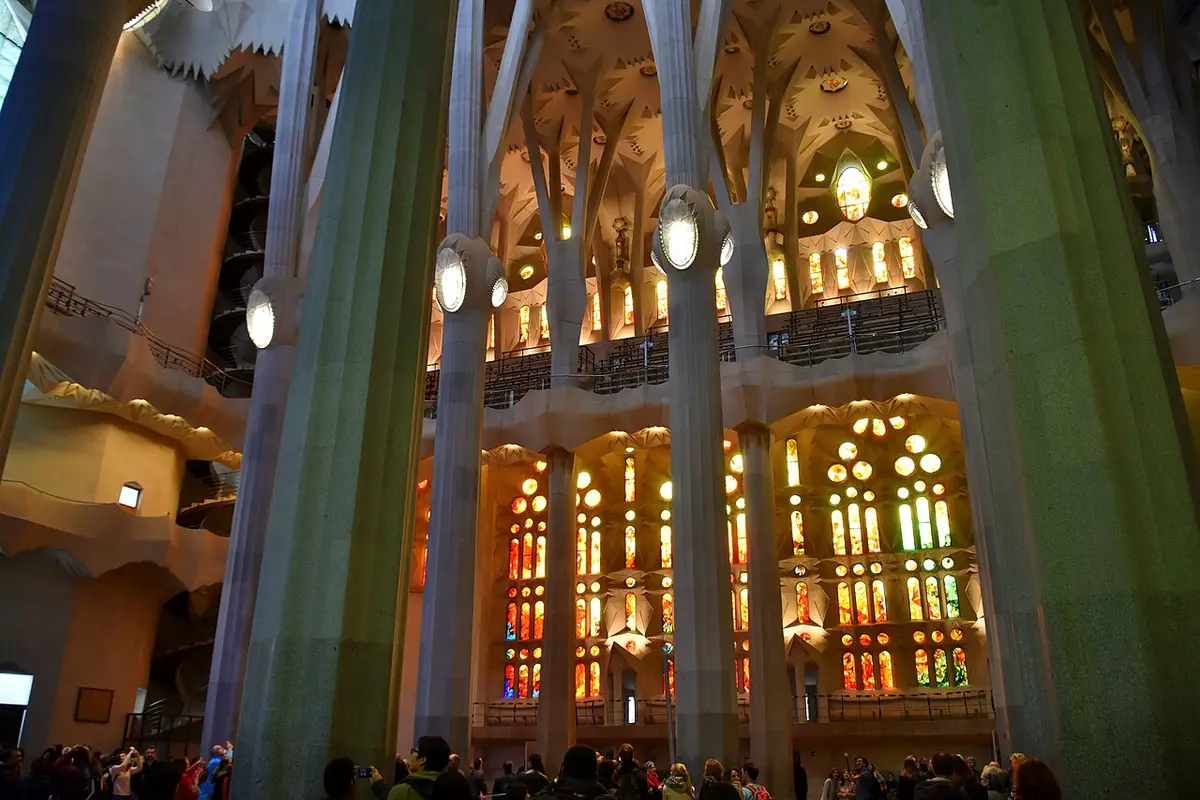 The nave of the Sagrada Família, tall branching columns in front of stained glass glowing orange and yellow