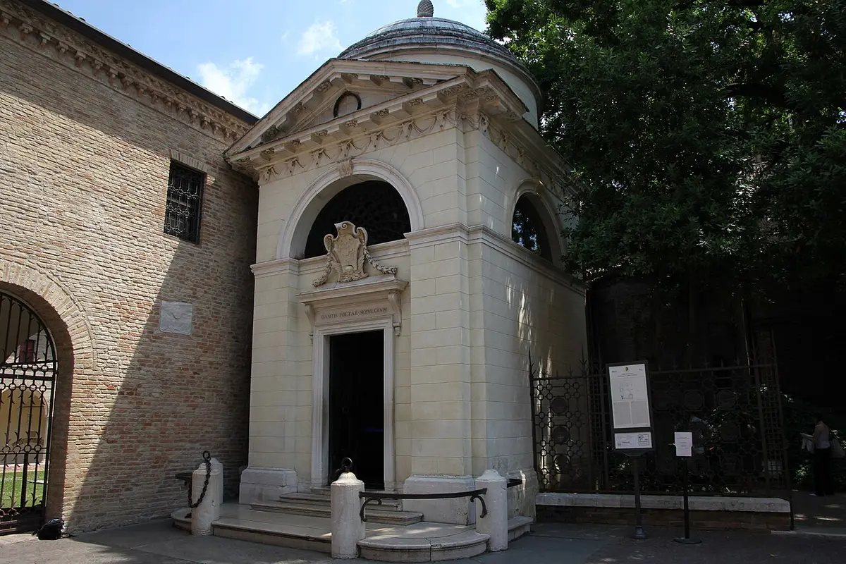 Dante’s small white neoclassical tomb with a dome, beside a brick wall in Ravenna