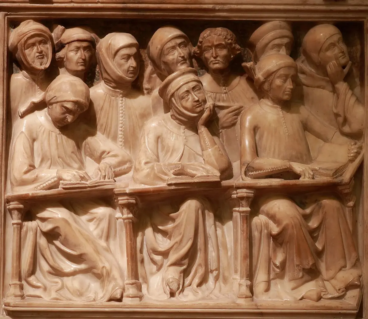 Marble relief of medieval students at their desks with open books, one resting his chin on his hand