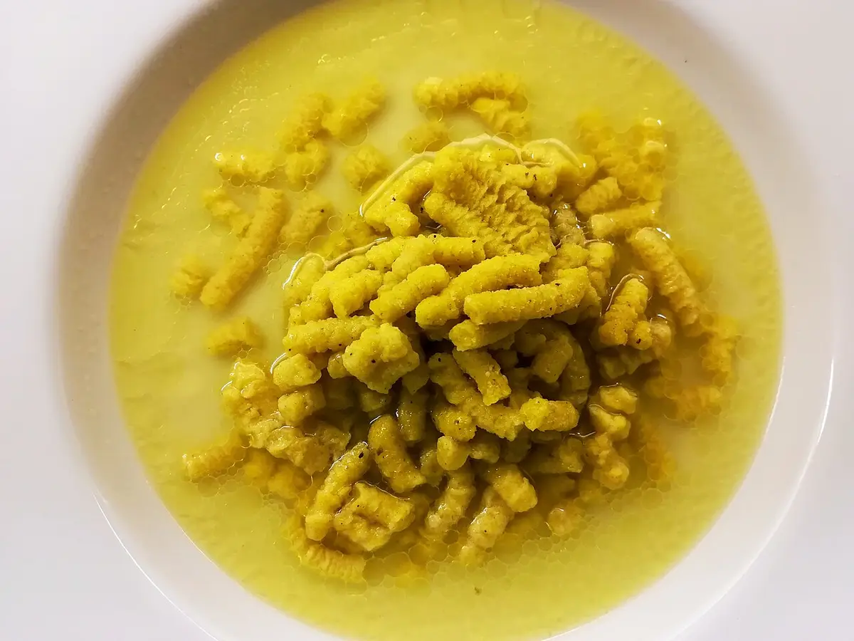 Passatelli, short rough strands of bread and cheese dough, in a bowl of broth