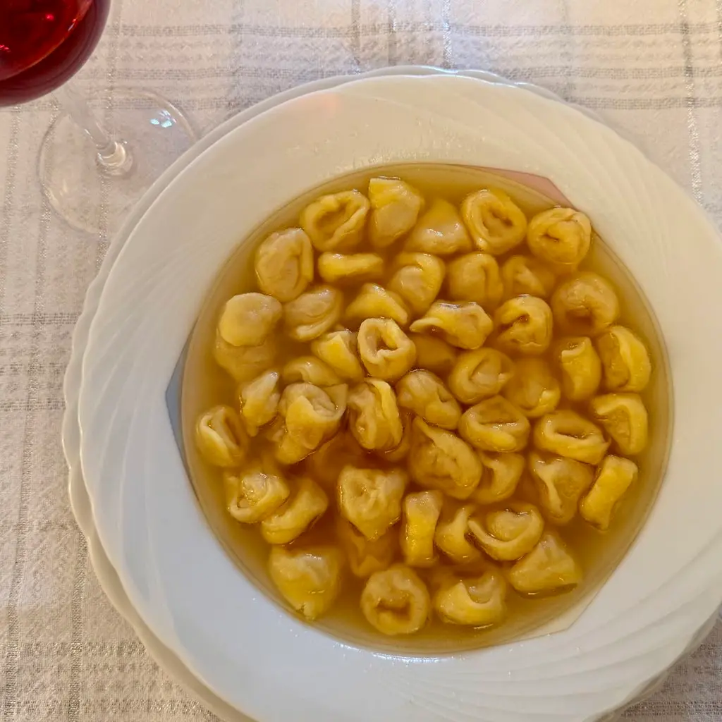 Tortellini in a golden broth in a white soup plate