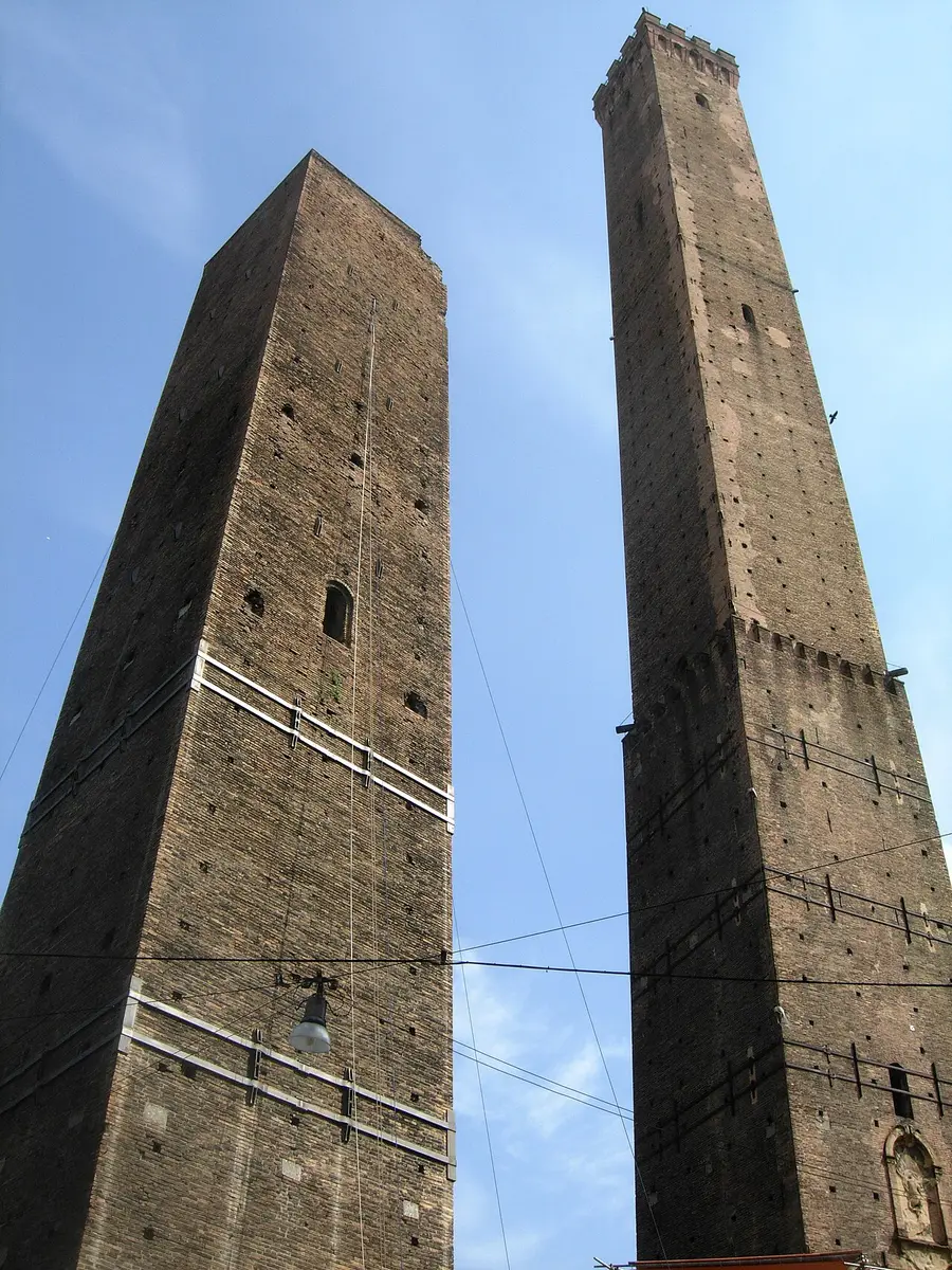 Bologna’s two medieval brick towers seen from below against a blue sky