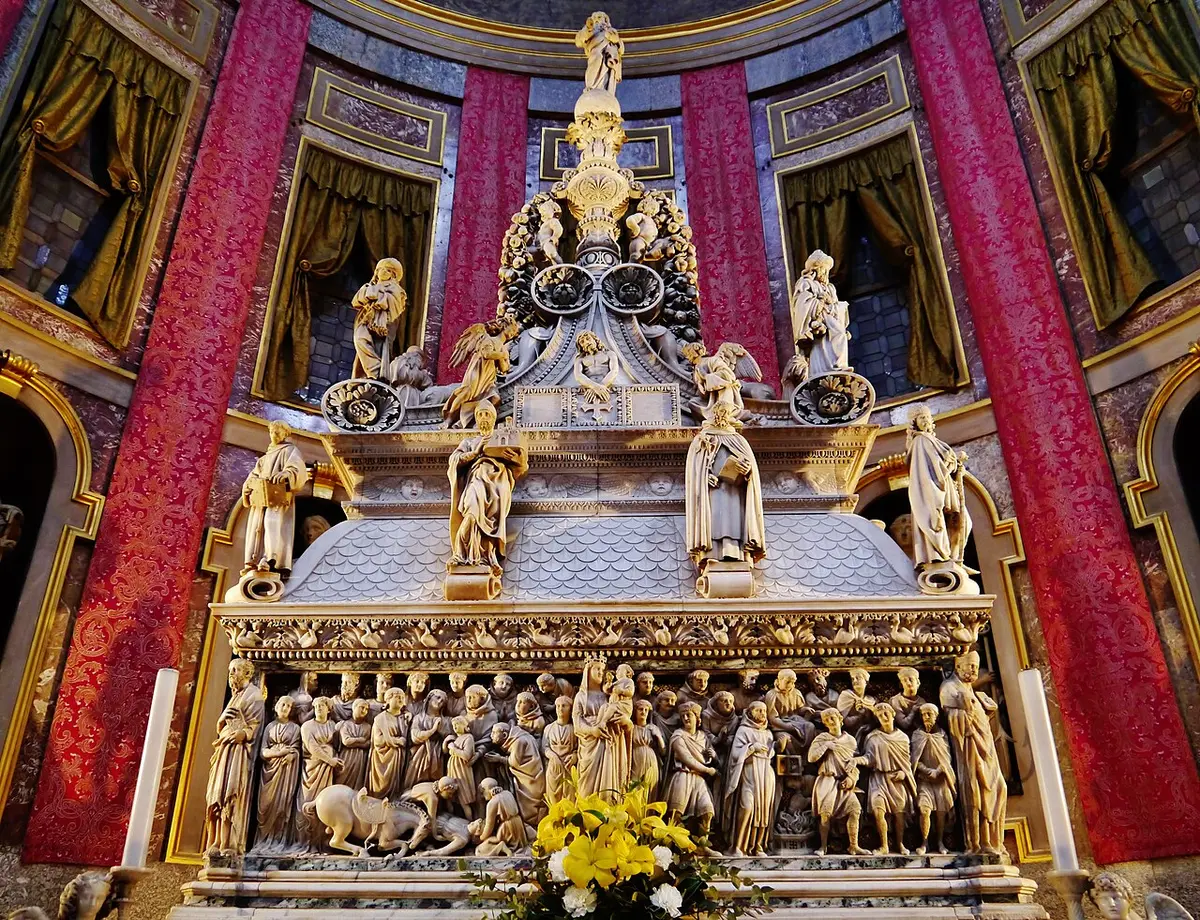 The marble tomb of Saint Dominic, covered with carved reliefs and small statues, in front of red drapes