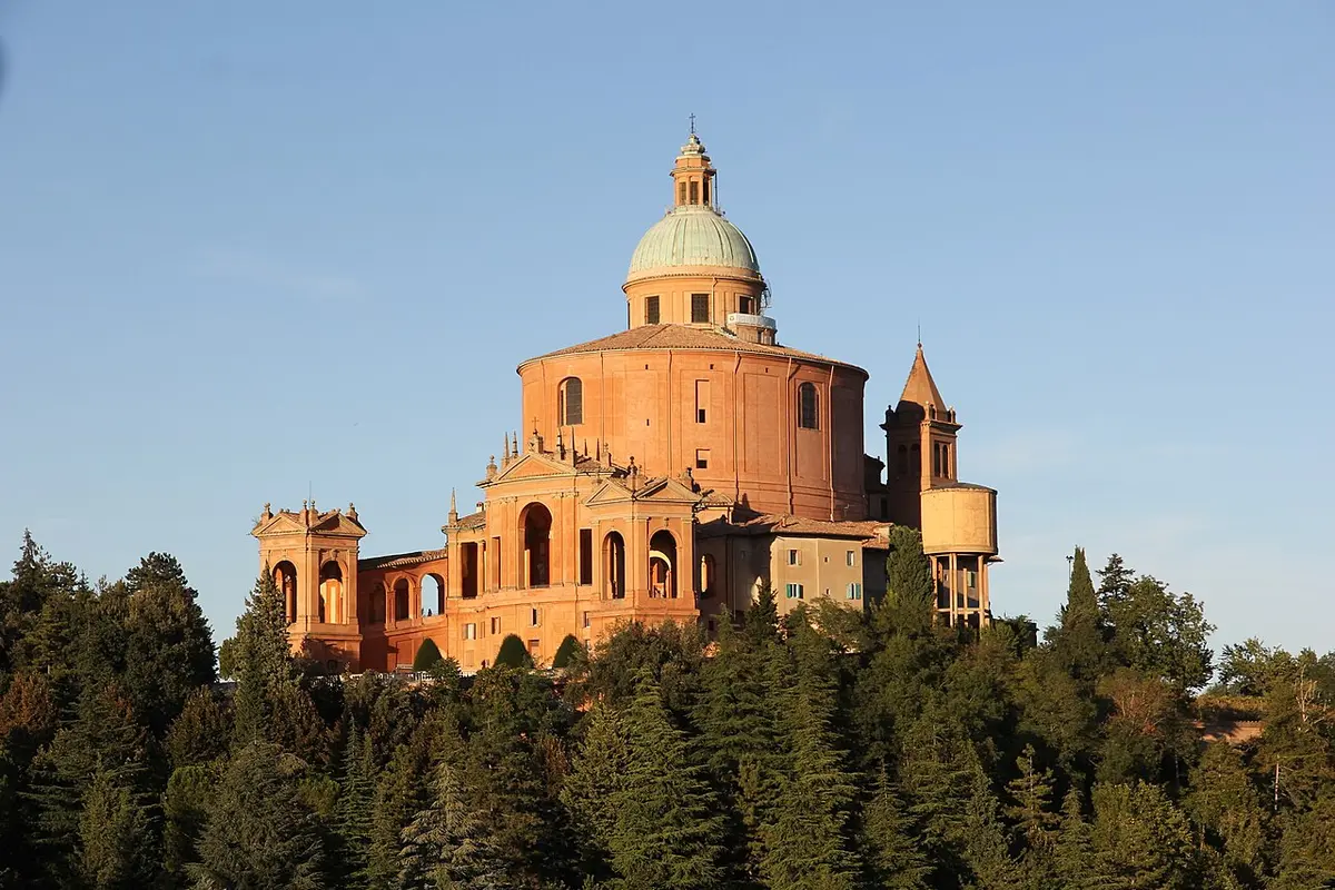 The domed brick Sanctuary of the Madonna di San Luca on a wooded hilltop in evening light