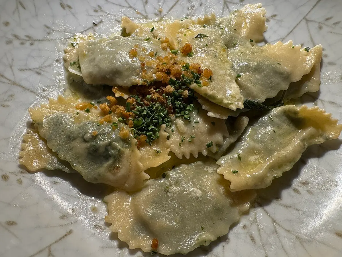 Schlutzkrapfen, half-moons of pasta with a green spinach filling, sprinkled with chives