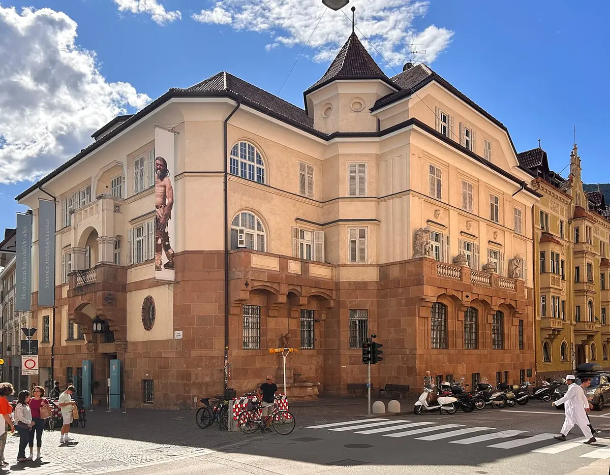 The South Tyrol Museum of Archaeology, a former bank building on a street corner, with a banner of the iceman