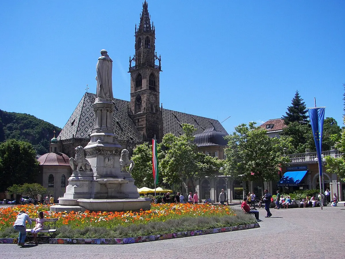 Piazza Walther with the statue of Walther von der Vogelweide, flower beds and the cathedral tower behind