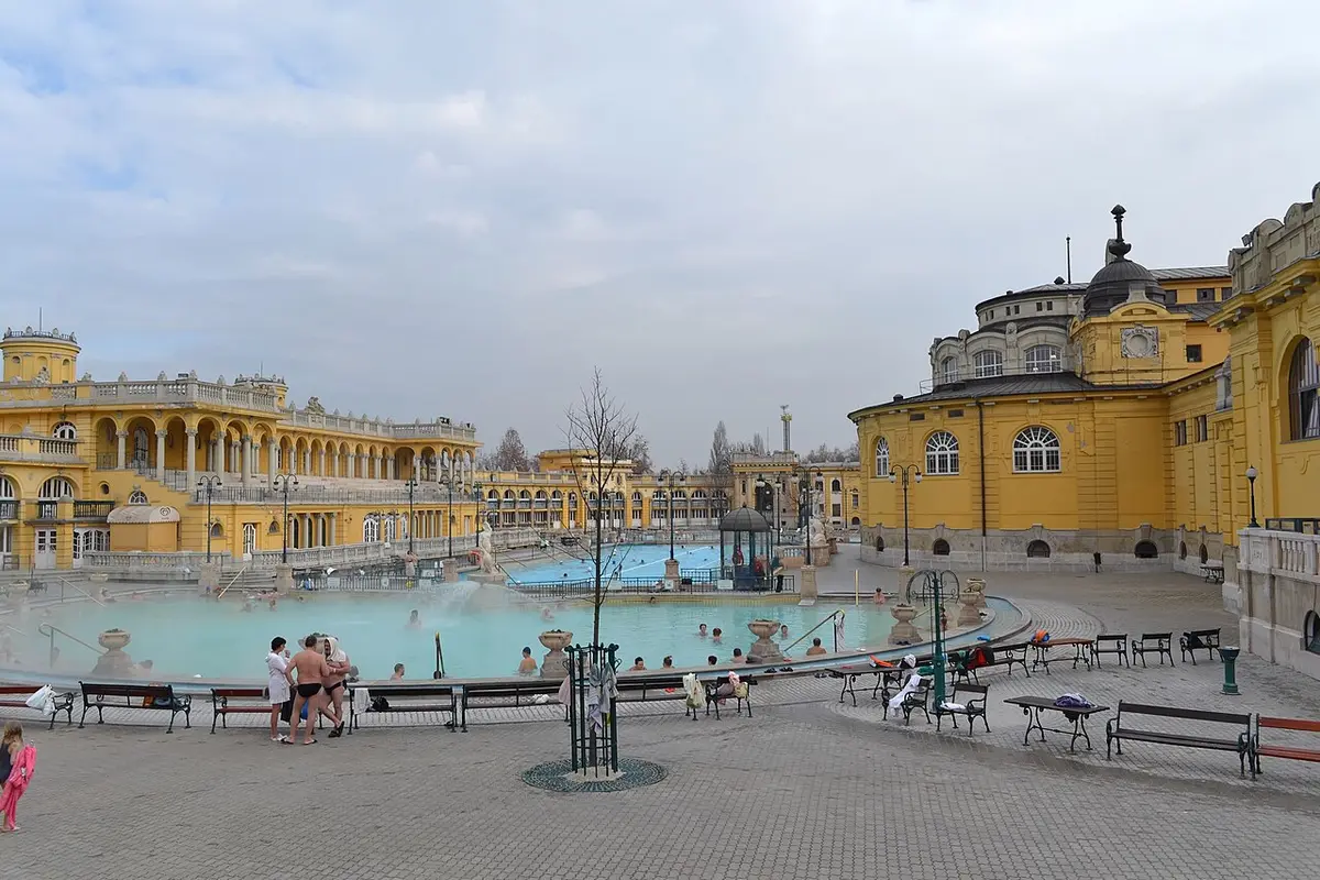 Steam rising from the outdoor pools of the Széchenyi Baths in winter, the yellow neo-baroque wings around them