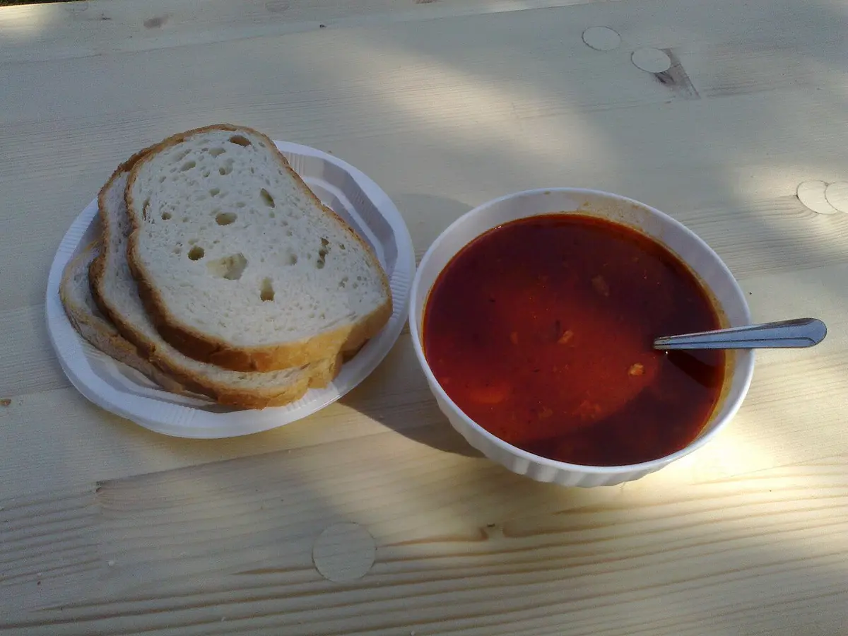 A bowl of red goulash soup with beef and potatoes