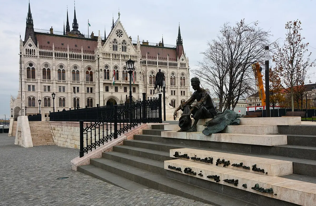 Bronze statue of the poet Attila József sitting on the embankment steps, the Parliament behind