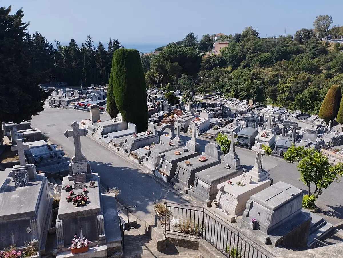 Terraces of white tombs and cypress trees in the Cimetière du Grand Jas, on a green hillside