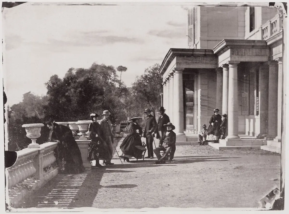Old photograph of a group in Victorian dress on the balustraded terrace of a villa with a columned porch