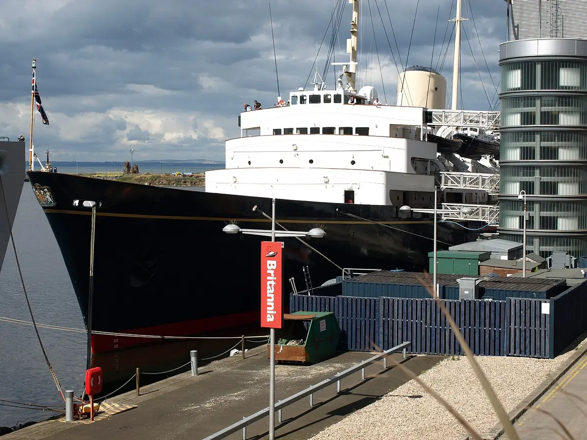 The dark blue hull and white decks of the Royal Yacht Britannia moored at Leith, dressed with flags