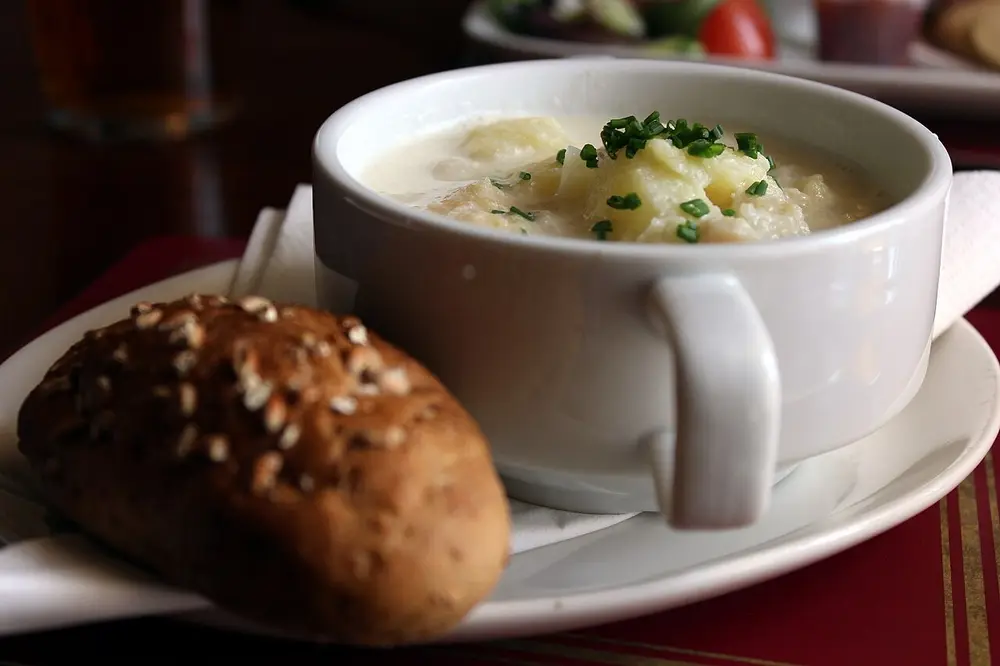 A bowl of Cullen skink, a creamy smoked haddock and potato soup, with a bread roll