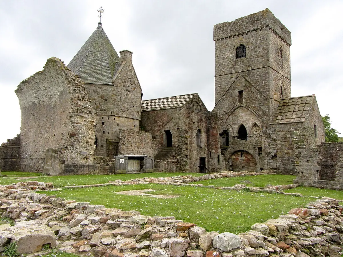 The stone church and tower of Inchcolm Abbey on a green island, with a low stone wall in front