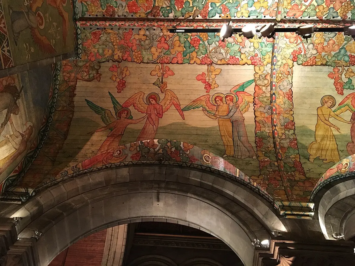Painted angels among vines and grapes on the vault above a stone arch in the Mansfield Traquair Centre