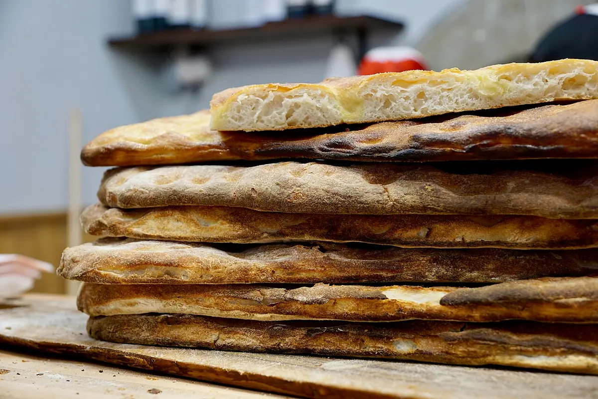 Sheets of Tuscan flatbread stacked on a wooden board in a bakery