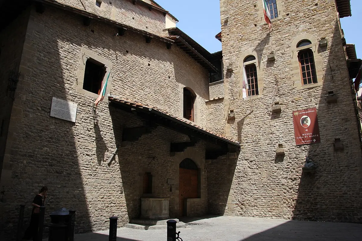 A marble plaque on a stone wall carved with Dante’s line about being born and raised on the Arno