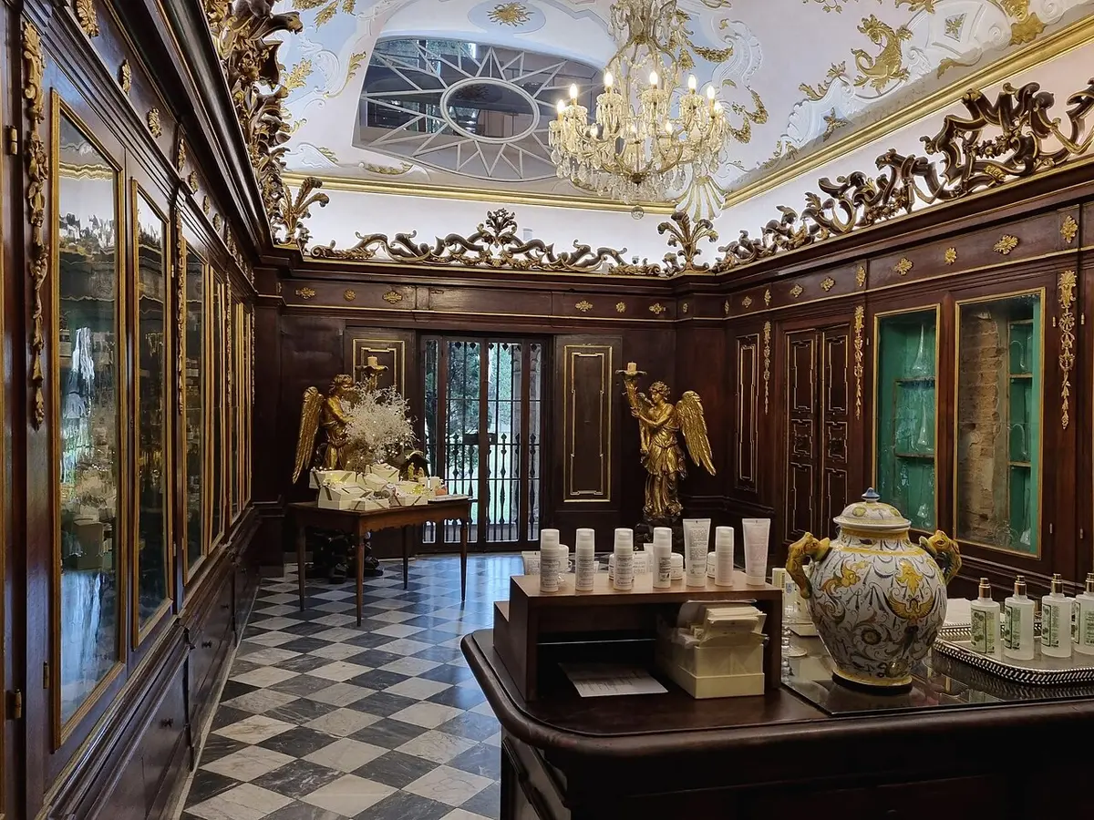 A room of the Santa Maria Novella pharmacy with carved wooden cabinets, gilded angels and a chandelier