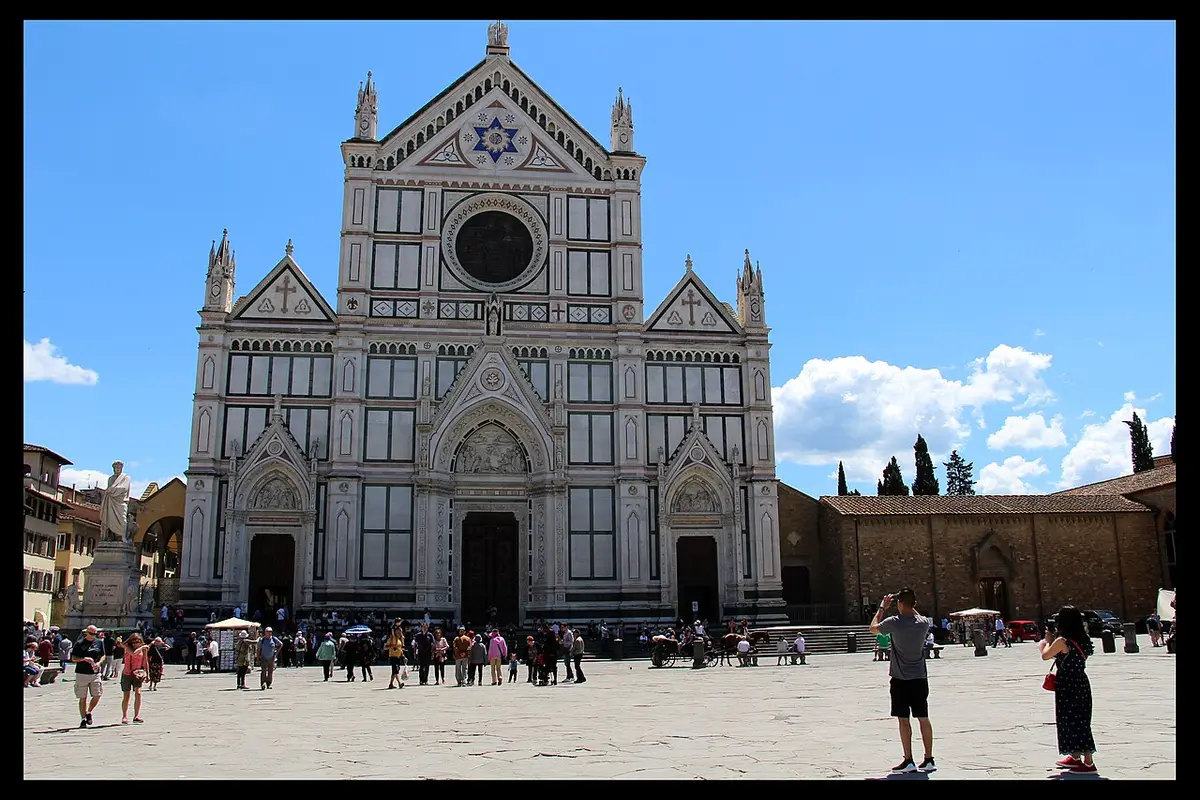 The white, green and pink marble front of the Basilica of Santa Croce above its wide square