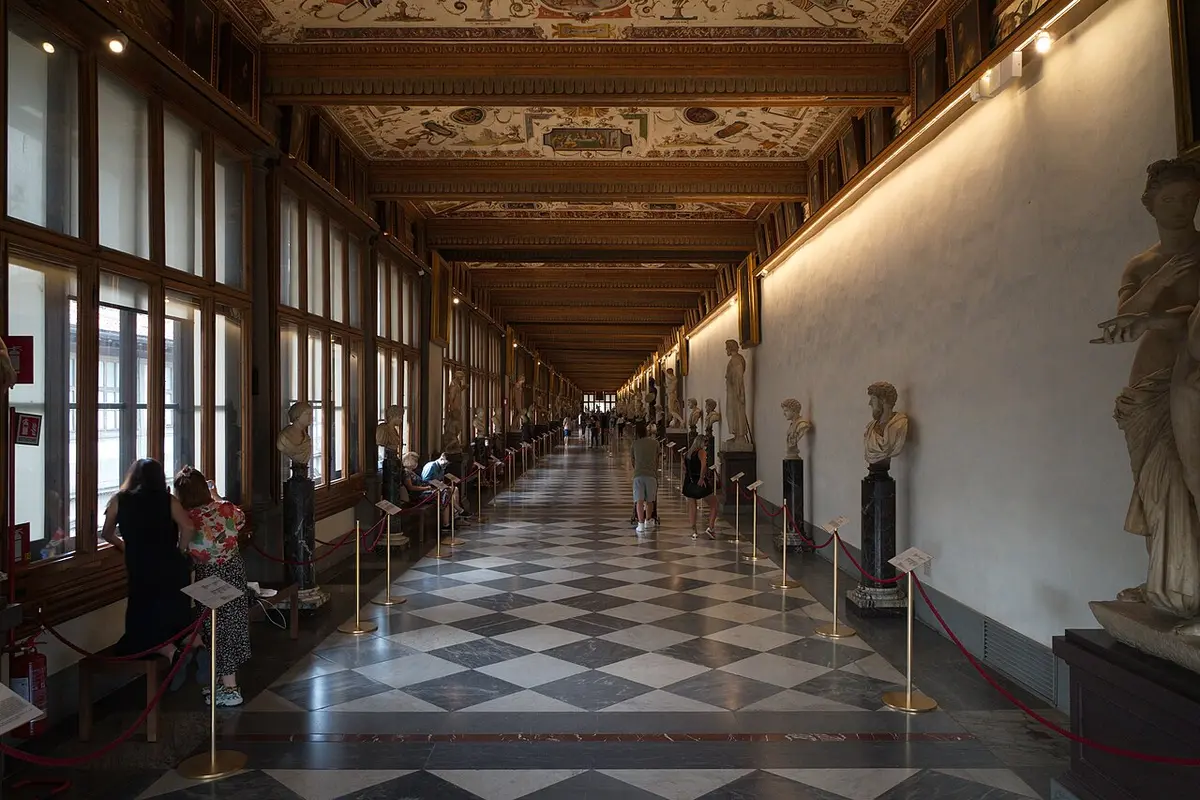The long east corridor of the Uffizi, lined with Roman busts and statues under a painted ceiling