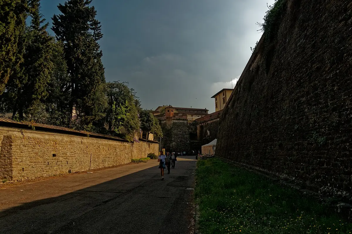 Via di Belvedere, a quiet lane running beside the high stone walls of Forte di Belvedere, cypresses on the other side