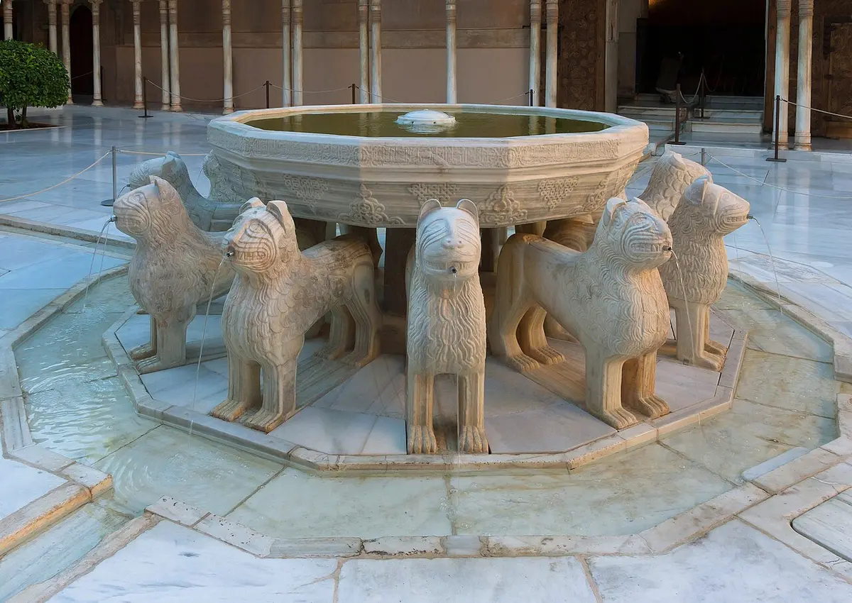 Twelve marble lions holding up a round stone basin in the middle of a marble court
