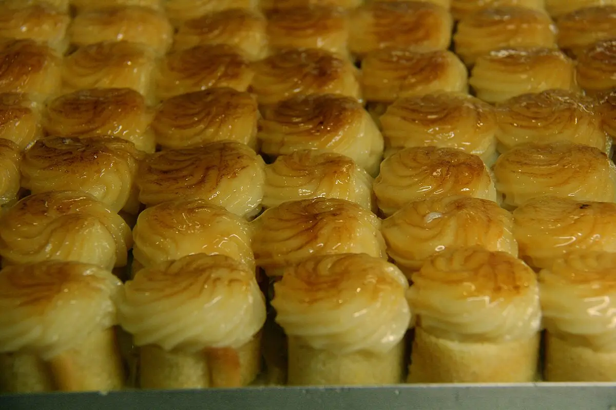 Rows of small rolled sponge cakes topped with toasted cream