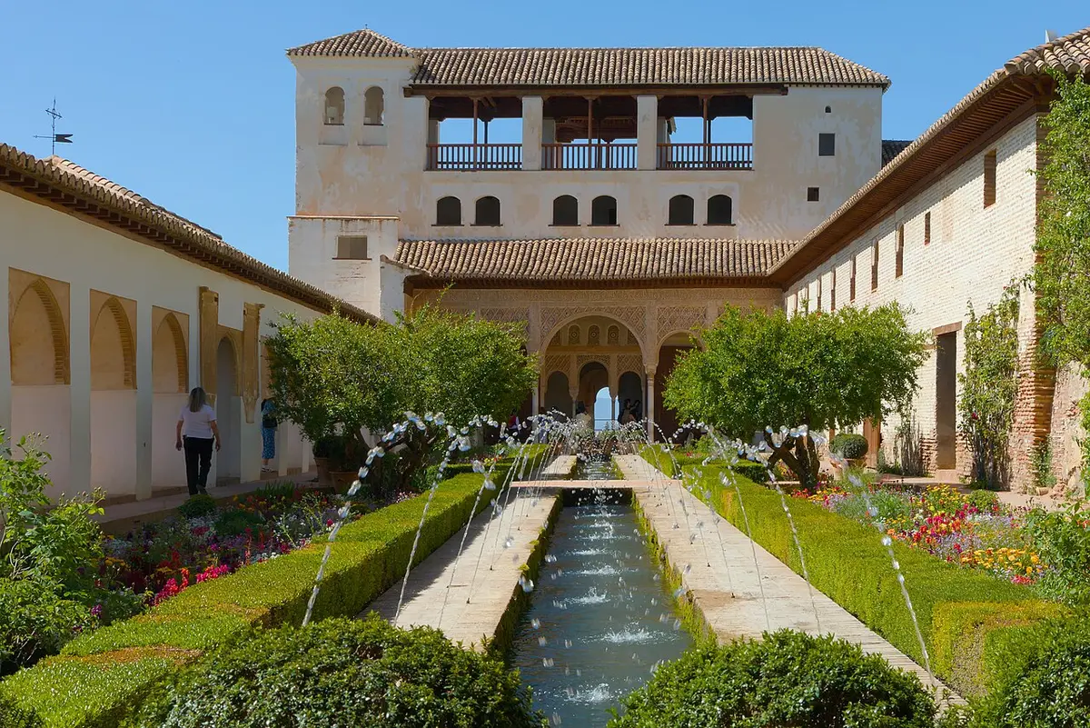 A long pool lined with jets of water and flower beds leading to an arcaded pavilion in the Generalife