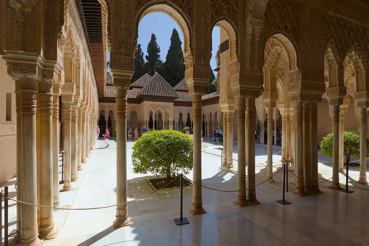 Slender marble columns and carved arches around the Court of the Lions, with a pavilion at the far end