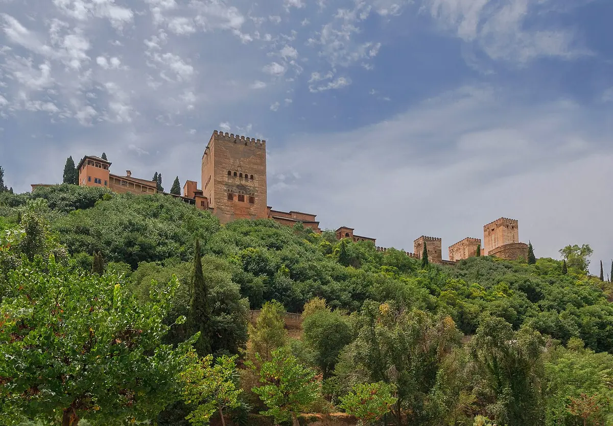 The towers of the Alhambra above a wooded slope, seen from below
