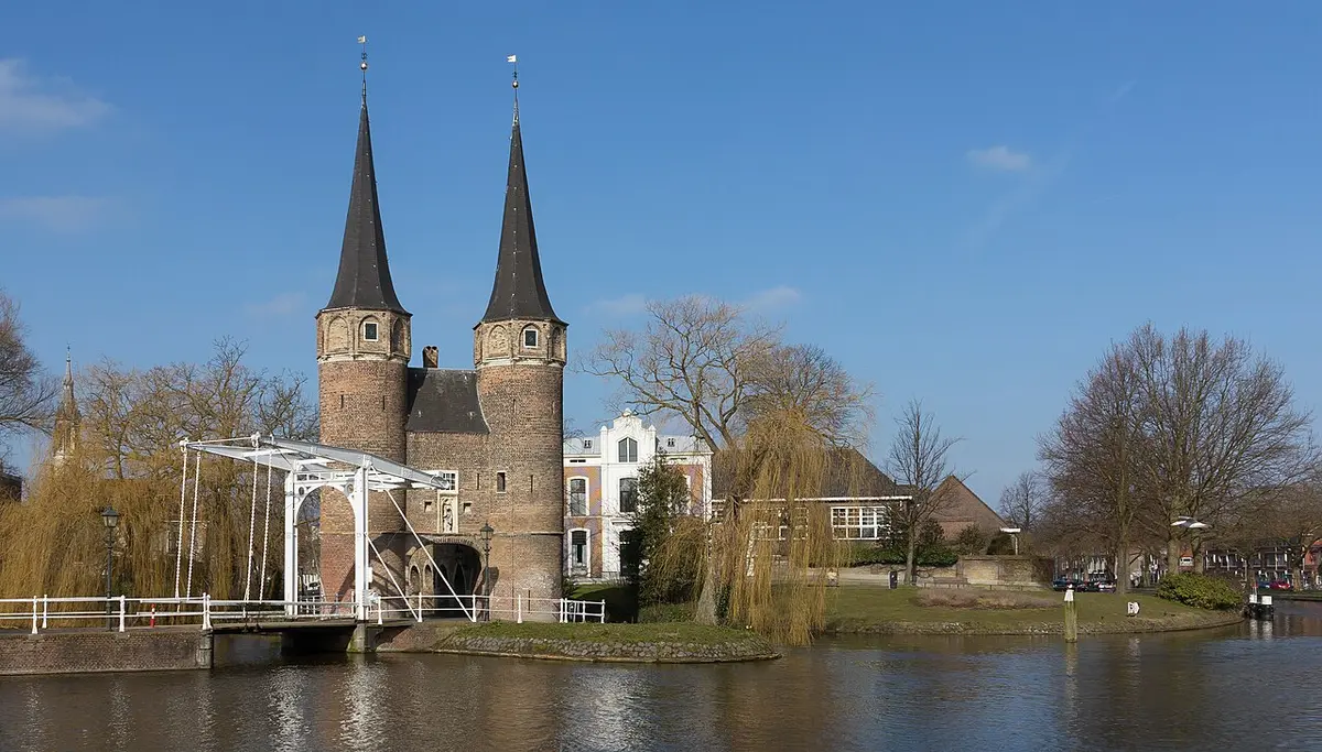 The Oostpoort in Delft, a brick gate with two pointed towers, beside a white drawbridge over the water