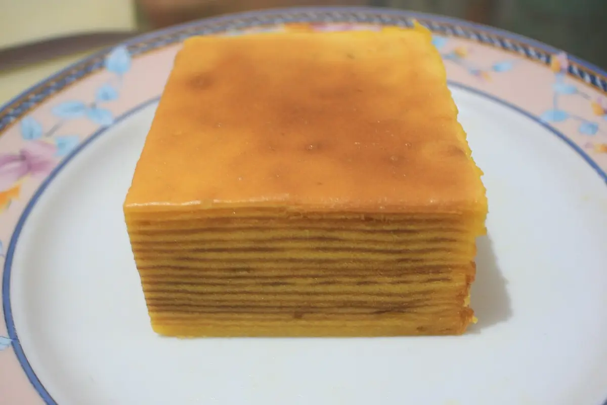 A block of spekkoek, a spiced cake of many thin golden and brown layers, on a plate