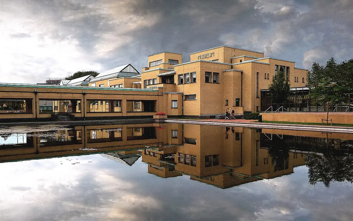 The pale brick Kunstmuseum Den Haag, a low building by Berlage, reflected in its pond