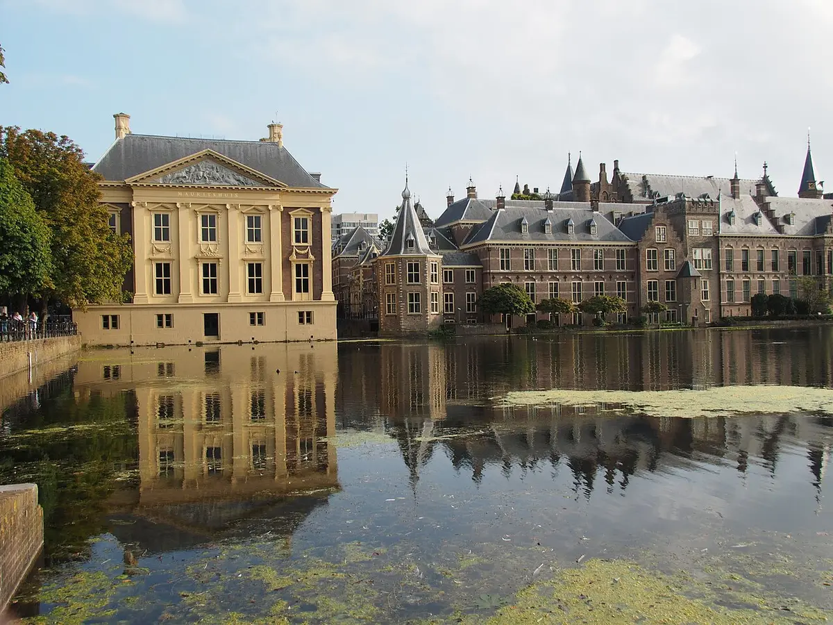 The square classical Mauritshuis reflected in the Hofvijver, with the Binnenhof beside it