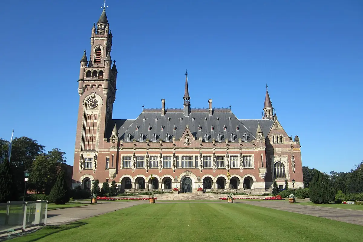 The Peace Palace, a red brick and stone building with a tall clock tower, behind a wide lawn