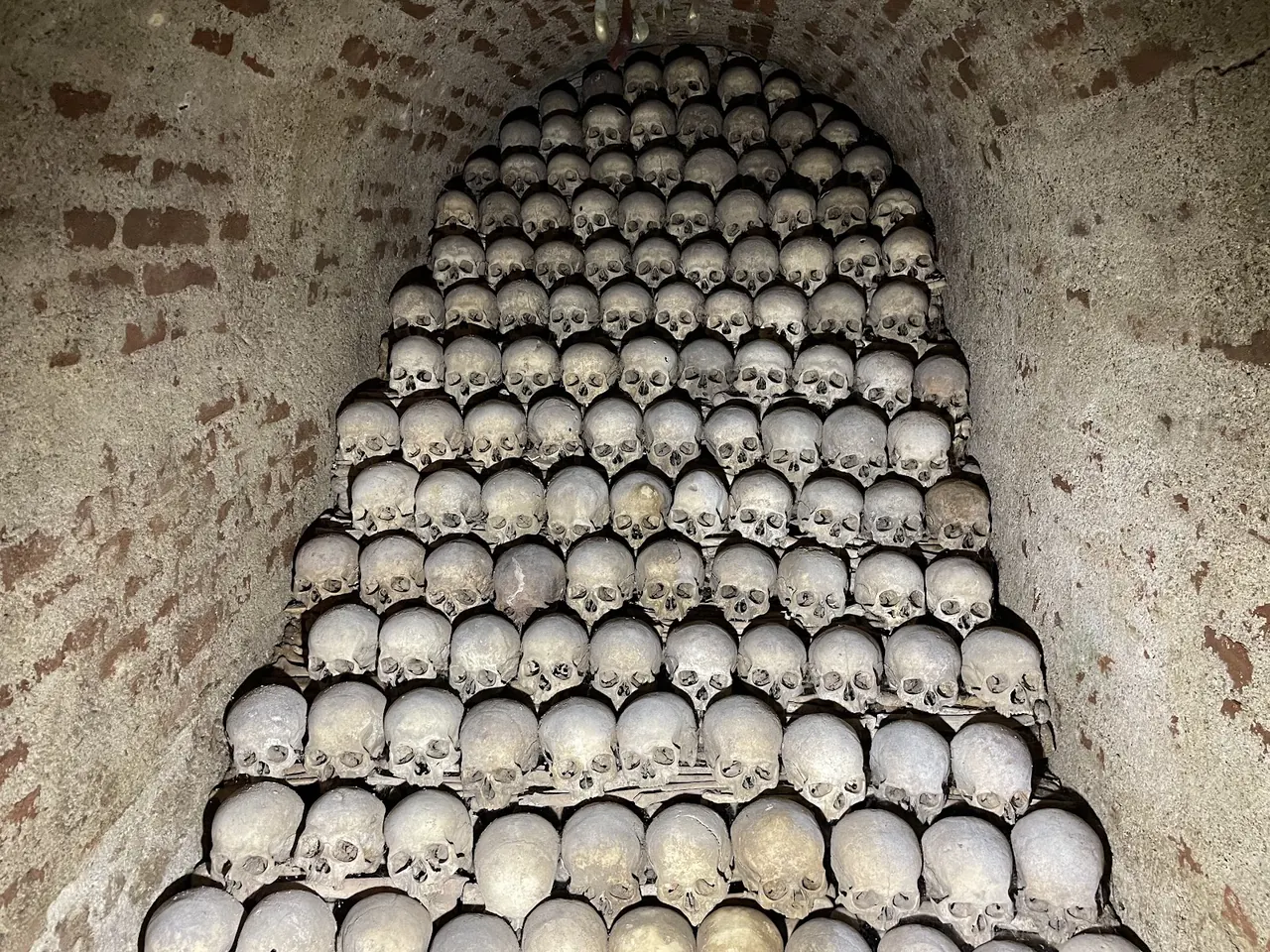 Rows of skulls stacked into a pyramid under a brick vault in the Brno Ossuary