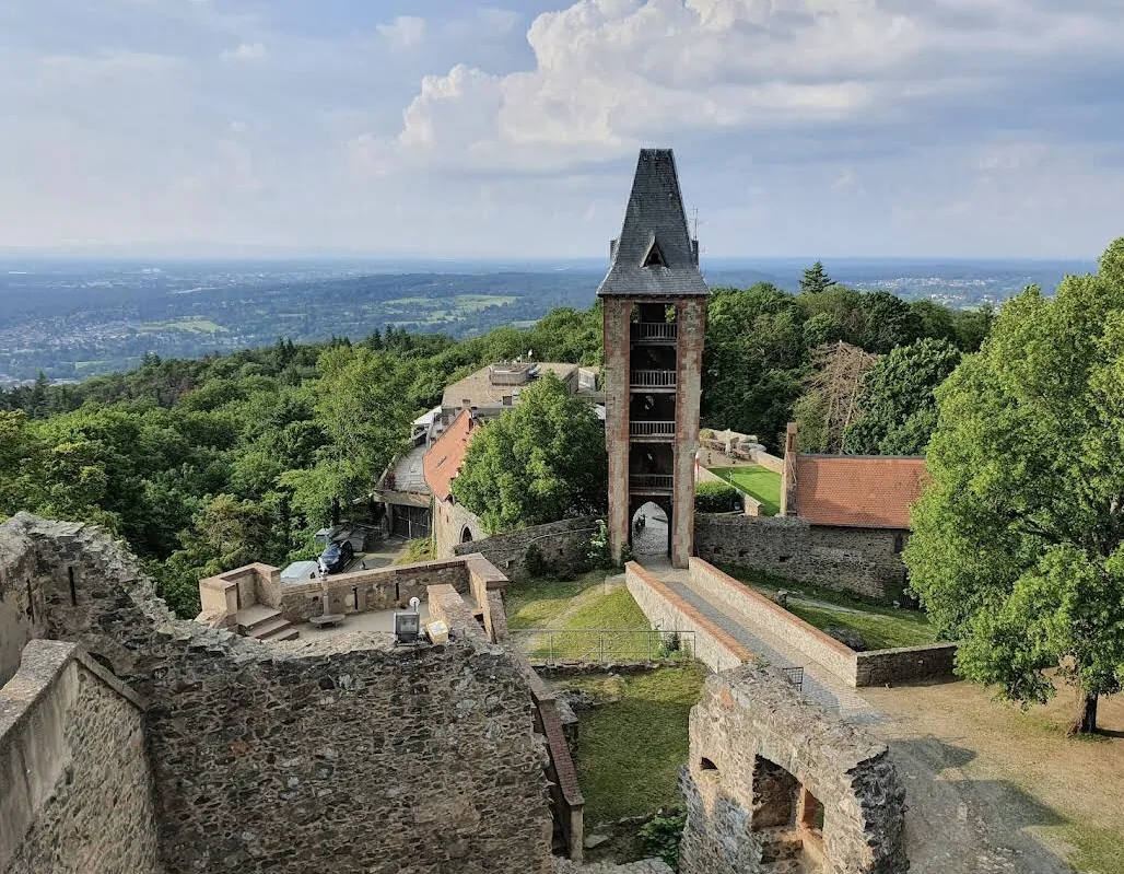 The ruins of Frankenstein Castle on a wooded hill, its tower over the walls and the plain far below