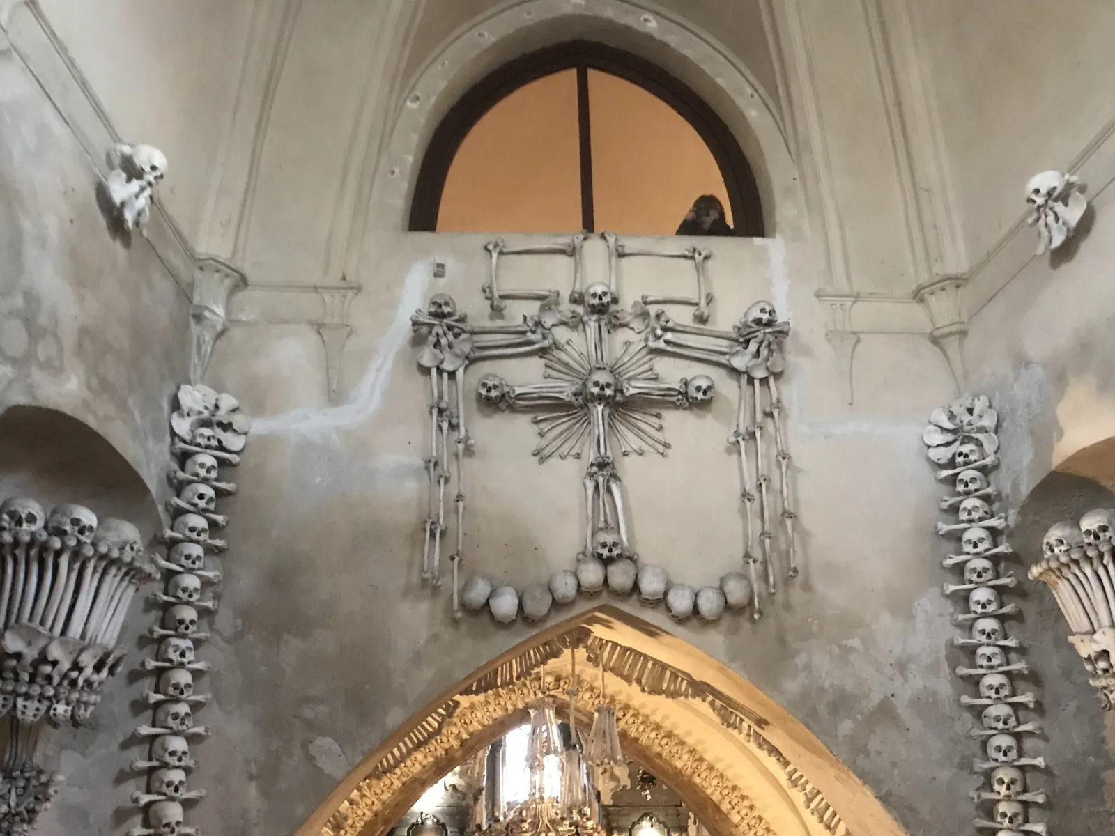 Inside the Sedlec Ossuary: garlands of skulls and bones on the walls, two chalices built of bones and a cross of bones under the window